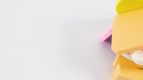 Abstract composition of colored cosmetic sponges, white background. Dolly sho Video stock 130243120