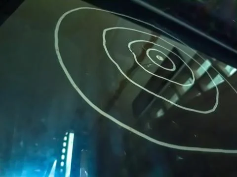 Abstract concentric ellipses on a reflective surface with a blue light back.. Stock Photos