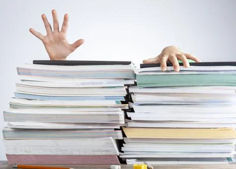 Abstract concept image showing a young student behind a large pile of test pr Stock Photos
