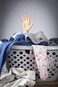 Abstract concept image with a woman's hand coming out of a basket full of clo Stock Photos