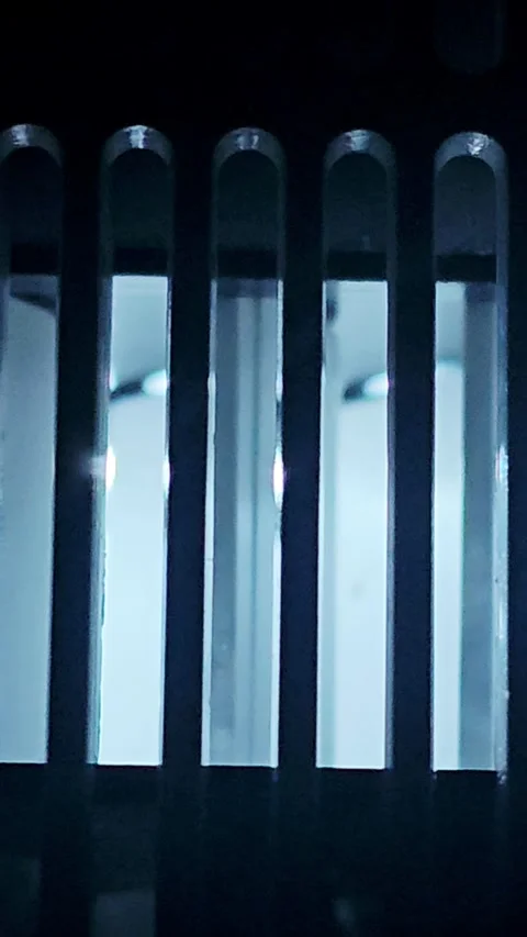 Abstract dark background featuring vertical metallic slots and glass prisms 스톡 동영상 345981201