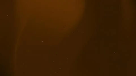 Abstract Dark Brown Background with Glowing Dust Particles and Warm Light Lea Stock Photos