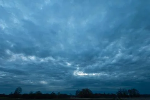 Abstract dark storm clouds over trees, spring evening Stock Photos