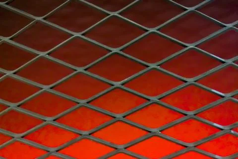 Abstract Diamond Patterned Metal Mesh Grate Over Red Background Stock Photos