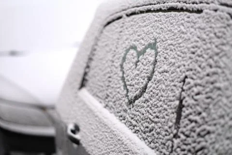 Abstract drawing of a heart on the side window of a car covered with wet snow Stock Photos