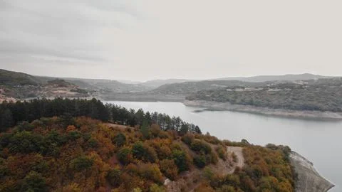 Abstract drone image showcasing bright fall foliage perched on jagged lakeside Stock Photos