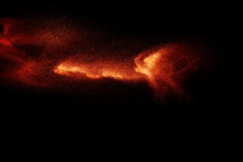 Abstract explosion of orange dust on black background. Freeze motion of orange Stock Photos