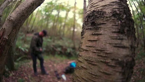Abstract extremely shallow focus shot of a man packing away tent beside a tree Vídeo Stock 166837985