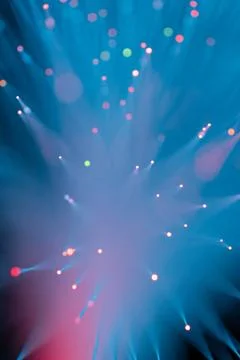 Abstract fiber optic light explosion with colorful bokeh dots on dark teal Stock Photos