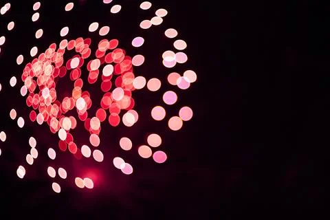 Abstract fireworks display with red and pink bokeh circles on dark night sky Stock Photos