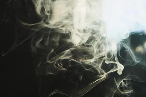 Abstract flowing smoke pattern with glowing light against a dark background Stock Photos