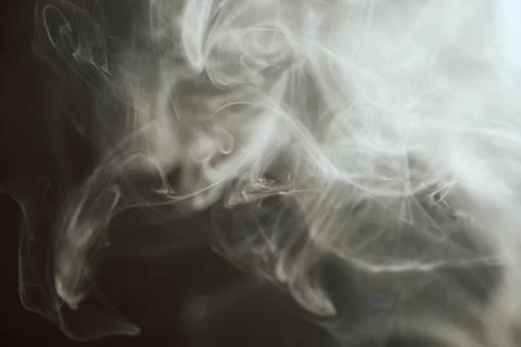 Abstract flowing white smoke patterns swirling on a dark background Stock Photos