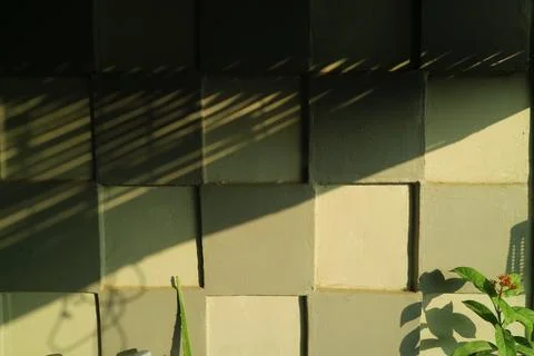 Abstract geometric shadow play on a square patterned concrete wall 写真素材