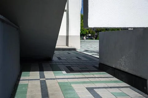 Abstract geometric shadows falling on green and grey tiled pavement between Fotos de archivo