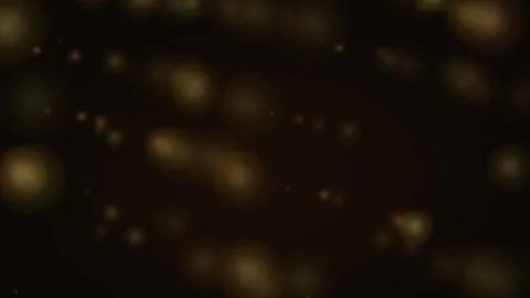 Abstract golden bokeh particles floating against a dark black background 库存影片 335149804
