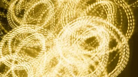 Abstract golden light trails creating circular patterns on dark background Stock Photos