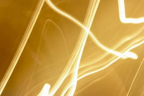 Abstract Golden Light Trails Creating Dynamic Patterns on Orange Background 写真素材