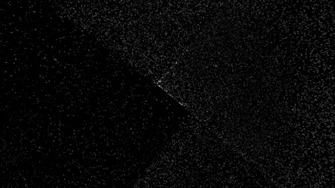 Abstract grainy texture with soft glowing white light spots on a dark black.. Stock Footage 346559372