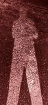 Abstract Human Shadow on Dark Maroon Textured Road Stock Photos