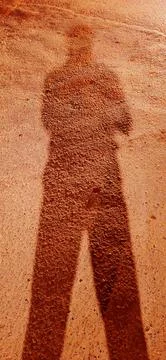 Abstract Human Shadow on Warm Brown Textured Road Stock Photos