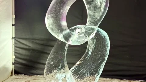 Abstract ice sculpture with smooth looping shape in a studio setup, lit against Video stock 333310310