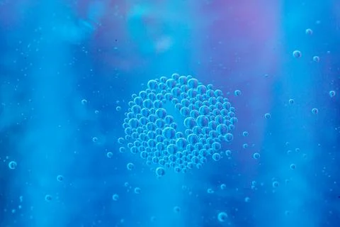 Abstract image of blue bubbles clustered in a ring formation against a vibr.. Stock Photos