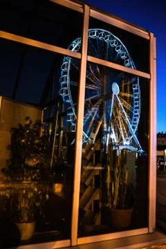 An abstract image containing reflection of a ferries wheel on a glass house w Stock Photos