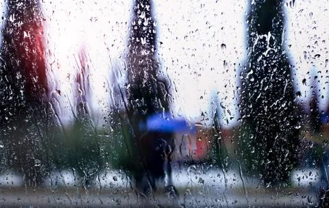 Abstract image of falling rain drops through the window with city background Stock Photos