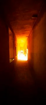 An abstract image featuring a narrow, dark corridor in an old stone building. Stock Photos