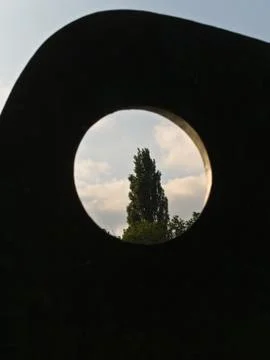 Abstract image of a tree and clouds seen through a hole of an object. Foto stock