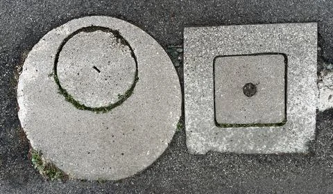 Abstract image of two concrete wall hatches located on the ground surface Stock Photos