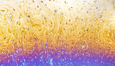 Abstract iridescent patterns of a soap bubble surface in vibrant yellow and.. 스톡 사진