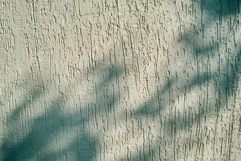 Abstract light and shadow pattern on a beige textured stucco wall Stock Photos