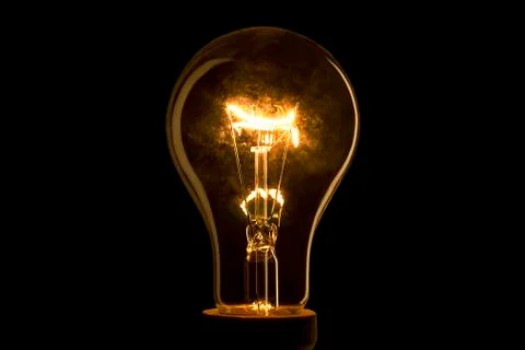 Abstract light bulb on the black background. Lamp light in the dark. Electric Stock Photos