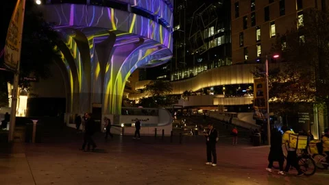 Abstract light patterns on Sydney building and passing pedestrians 6K Stock Footage 310949518