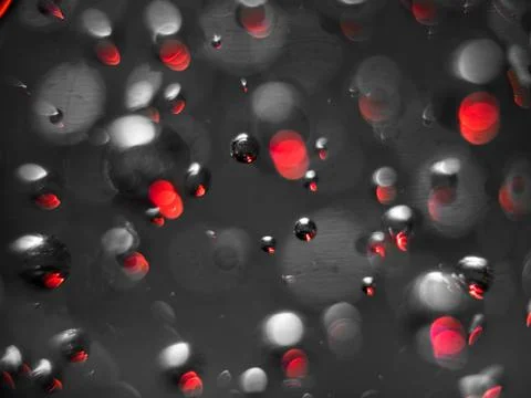 Abstract macro of air bubbles embedded in glass with red accents. Stock Photos