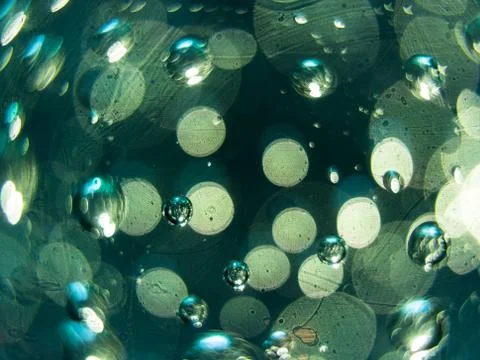 Abstract macro of air bubbles embedded in glass with green accents. Stock Photos