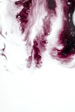 An abstract macro shot of deep red and maroon ink mixing and swirling in a .. Stock Photos