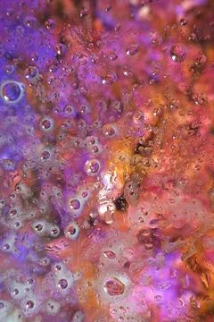 An abstract macro shot featuring droplets and vibrant shades of purple, ora.. Stock Photos