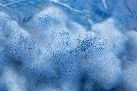 Abstract macro texture of white foam or cotton mixed with vibrant blue pigm.. Stock Photos