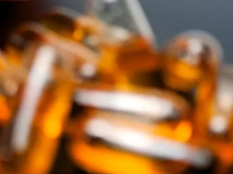 Abstract macro view of amber softgel capsules inside a transparent bottle, .. Stock Photos