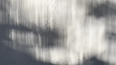 Abstract monochrome light reflection shimmers along textured gray concrete wall  스톡 동영상 333691234