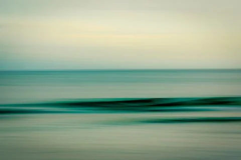 Abstract motion blur of ocean waves and sky in soft, muted tones. Stock Photos
