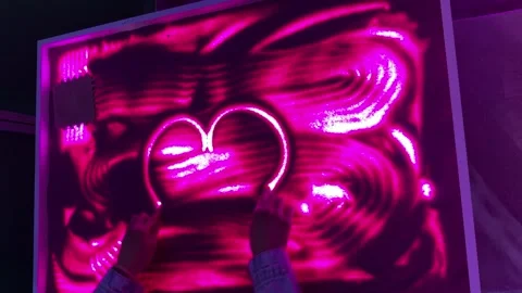 Abstract neon pink light pattern with hand-drawn design on glowing sand  Video stock 336407955