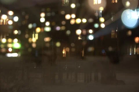 Abstract night city lights bokeh background through a window glass Stock Photos