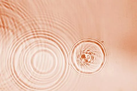 Abstract pattern of circles of drops on water, background of peach colored Foto stock