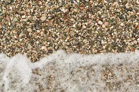 Abstract pattern created by various small stones, seashells, and wet sand. .. Stock Photos