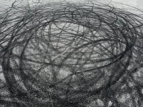 Abstract pattern of dark, swirling tire marks on a textured asphalt surface Stock Photos