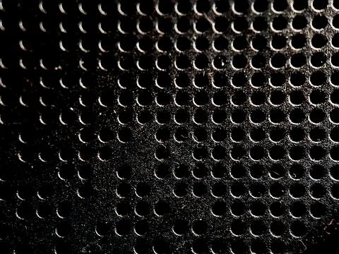 Abstract pattern of dark textured material with evenly spaced perforated ho.. Stock Photos