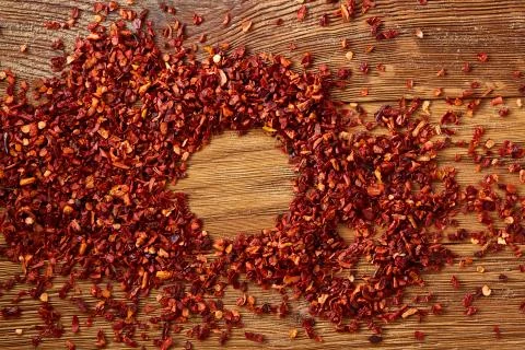 Abstract pattern of dried red hot chilly flakes on rustic wooden background, top Stock Photos